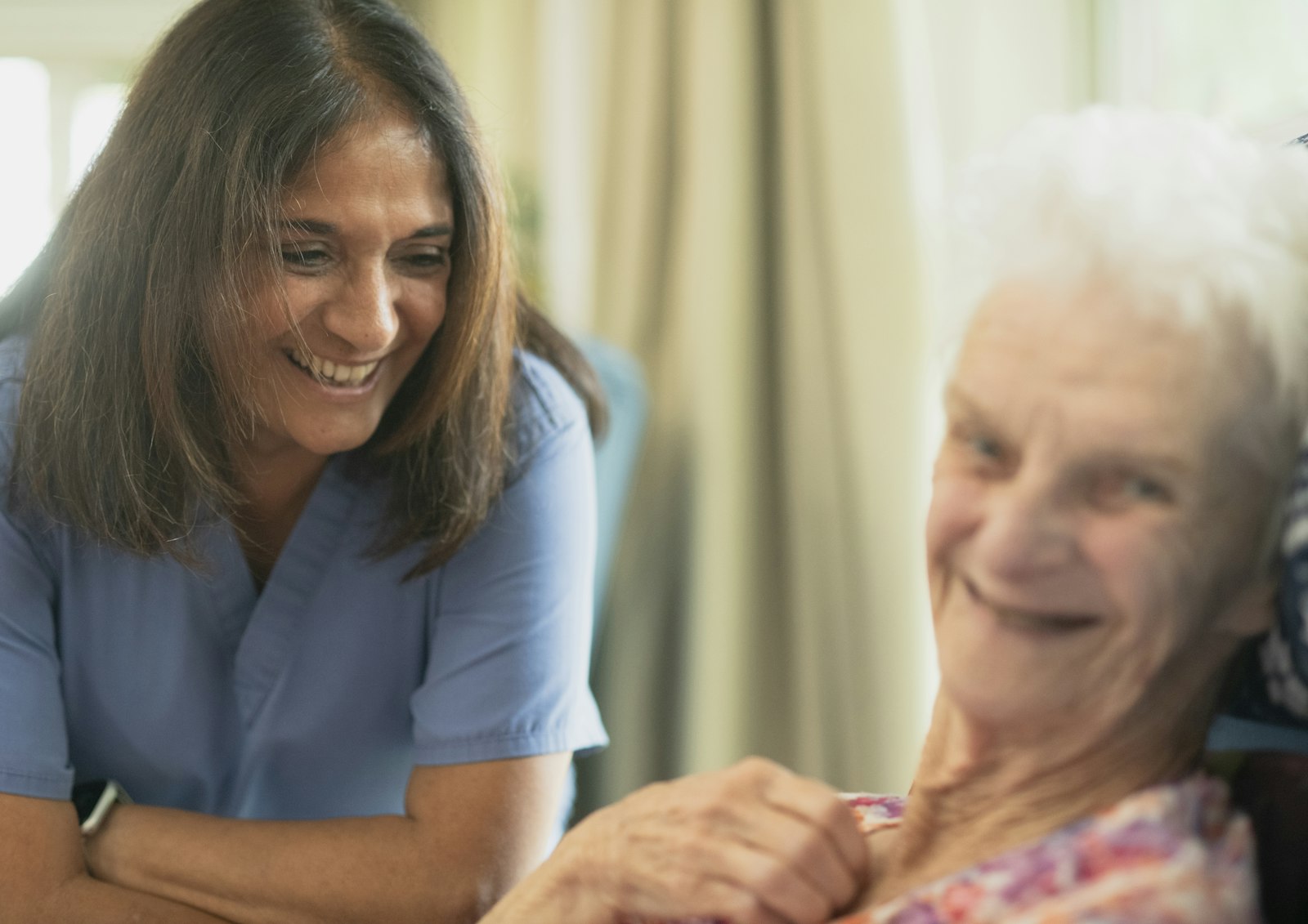 A caregiver sharing a laugh with an elderly resident
